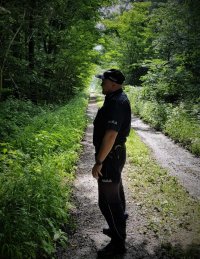 na zdjęciu: dzielnicowy mł.asp. Tomasz Domka patrzy w kierunku lasu